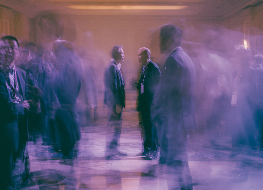 Motion-blurred founders in conversation at a busy conference
